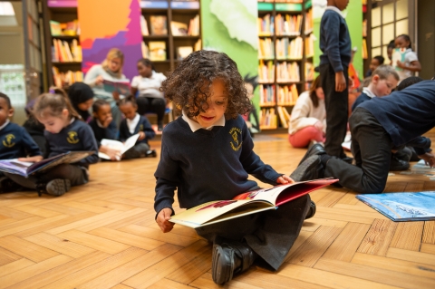 Boy reading sitting on the floor in library