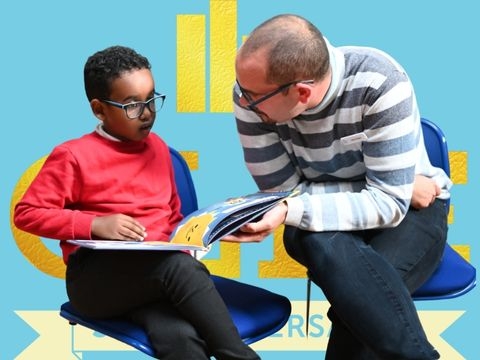 Man and boy discuss a book with CLPE logo in background